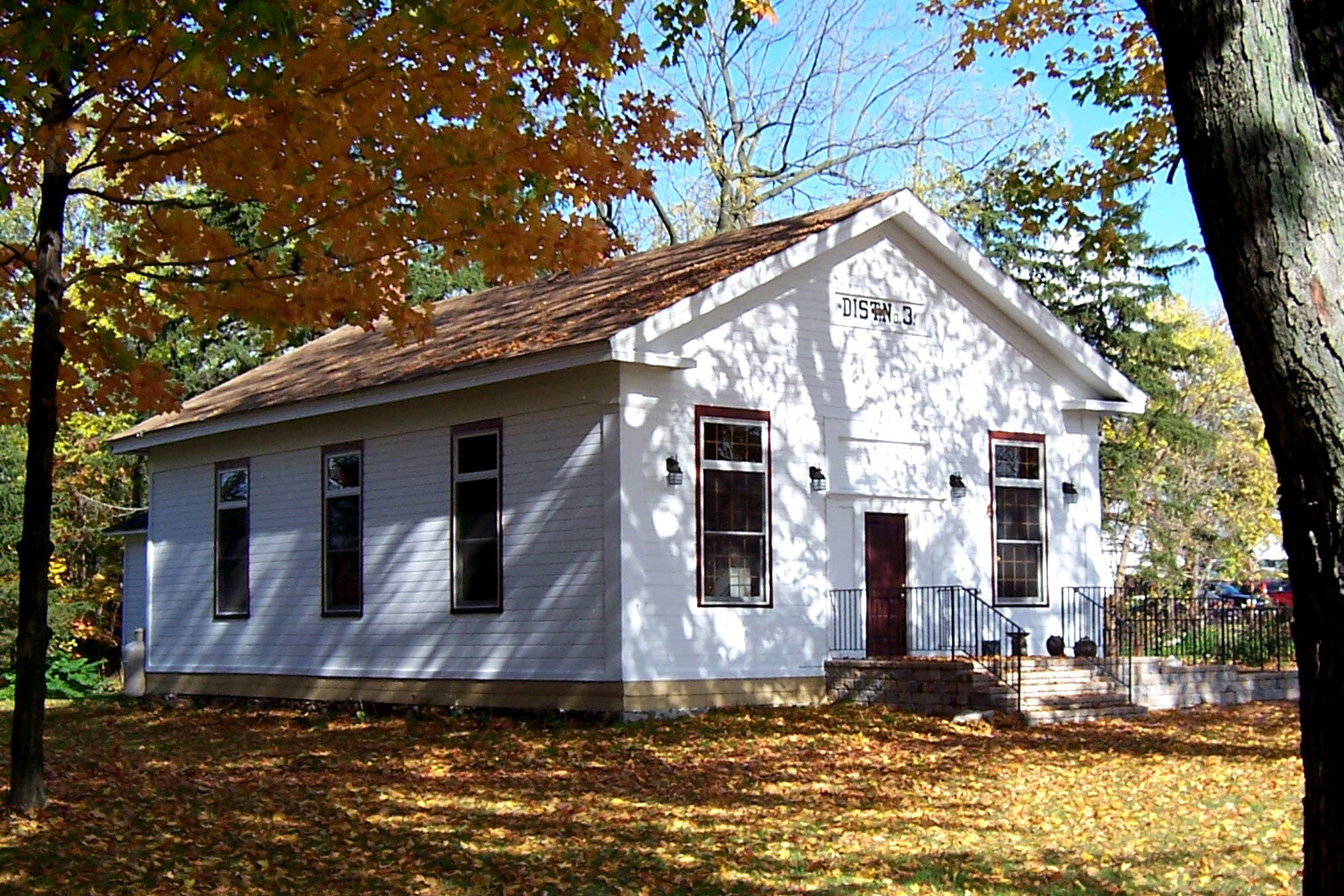 Old white schoolhouse building on a small hill in autumn, which has been converted into a pottery studio.