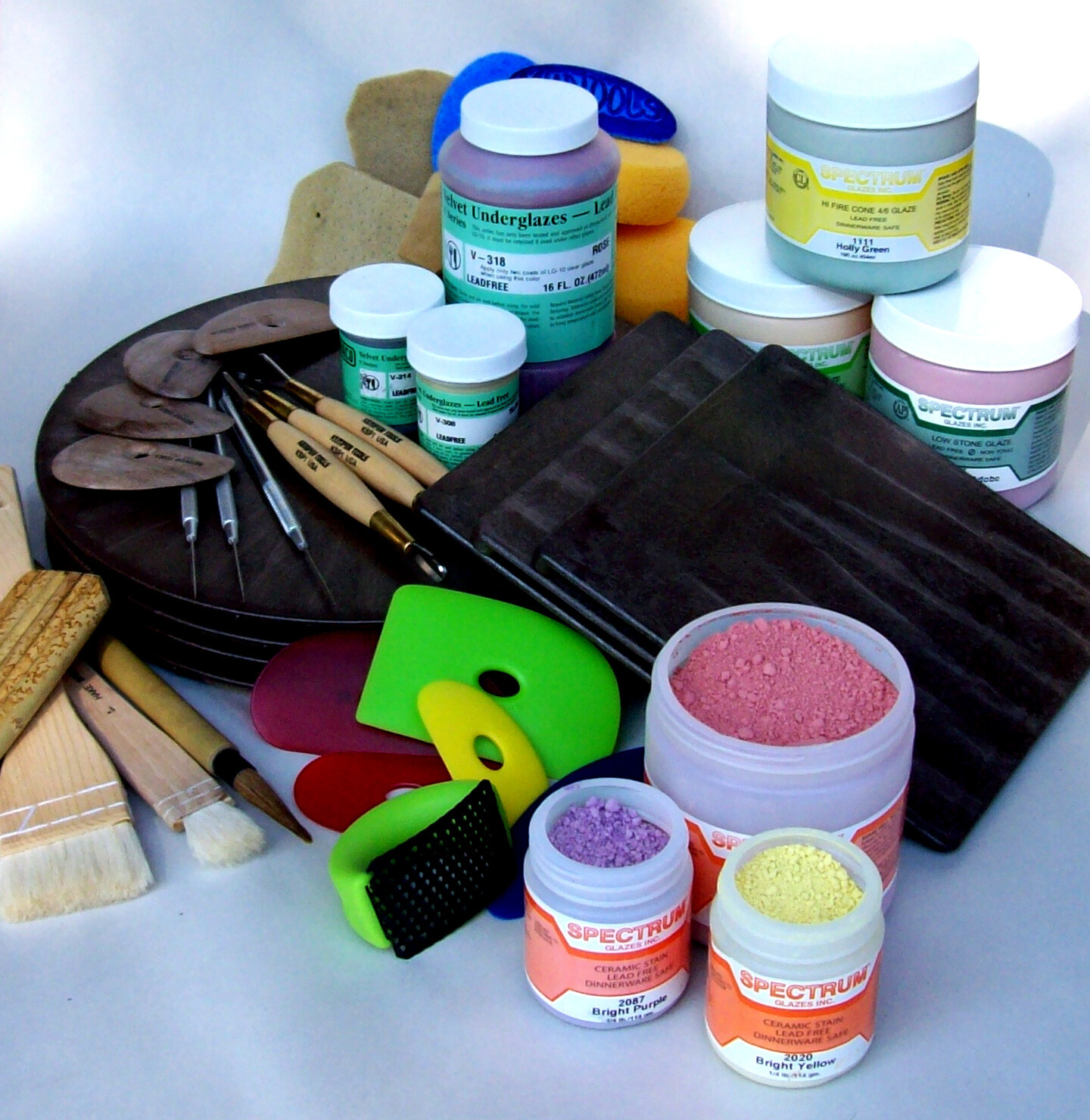Pottery supplies on a table, including sculpting tools, brushes, and glazes.