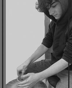 Black and white photo of a young man working with clay on a potter's wheel.